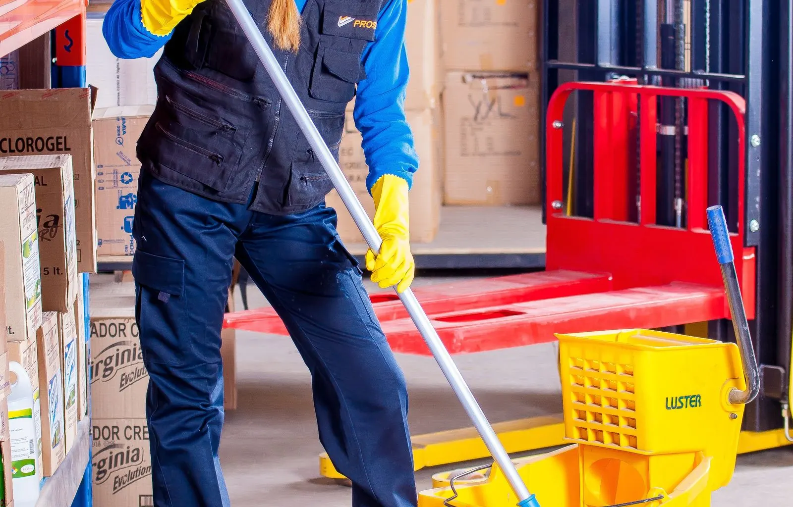 Uniformed janitor with commercial cleaning cart in office hallway Uniformed janitor with commercial cleaning cart in office hallway